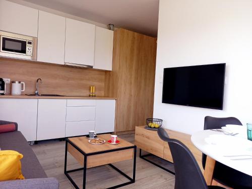 a kitchen and a living room with a table and a tv at BALT Marynarska 8 in Sarbinowo