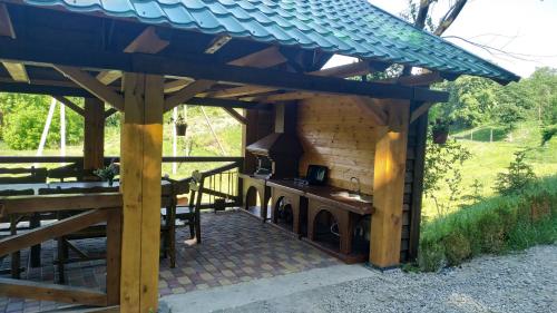 a barbecue under a wooden pergola with a stove at Zelenaya Usad`ba StavBor in Zavadivka