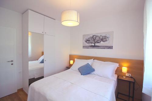 a bedroom with a white bed and a tree on the wall at Sun Apartments in Primošten