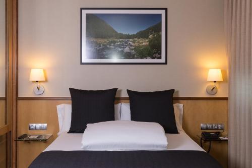 a bed in a hotel room with two lamps at Font D'Argent Pas de la Casa in Pas de la Casa
