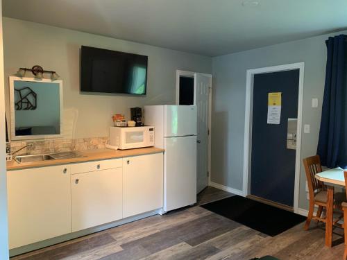 a kitchen with a white refrigerator and a microwave at Peaks Lodge in Revelstoke