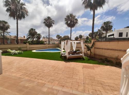 a backyard with a pool and a chair and palm trees at La Atalaya in Benalmádena