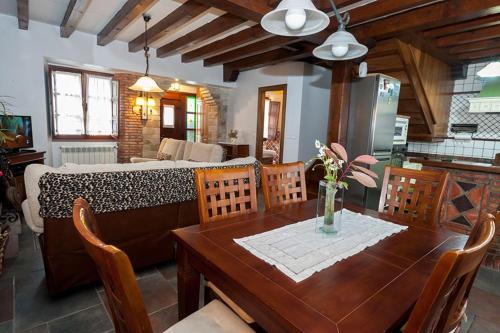 a dining room with a wooden table and a kitchen at Viviendas La Campa in Comillas