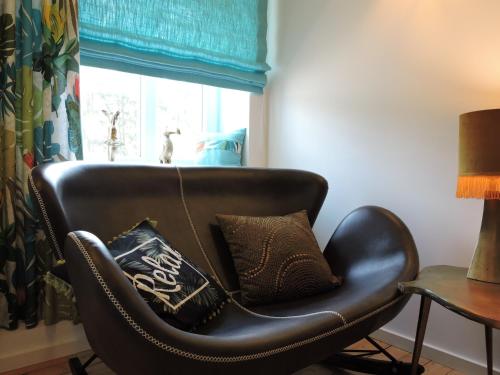 a black leather chair with pillows on it in front of a window at Seveniger Mühle in Sevenig