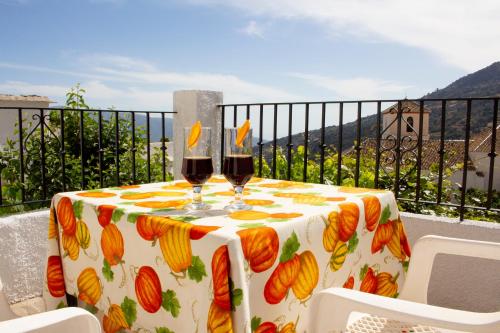 a table with two glasses of wine on a balcony at Puerta Bubión Apartamentos in Bubión