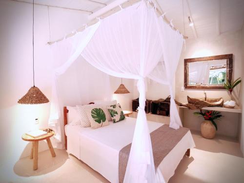 a bedroom with a white bed with a canopy at Trancoso House - Hotel Boutique in Trancoso