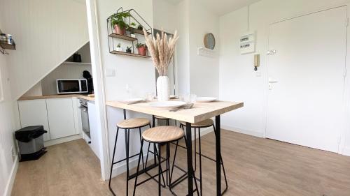 a kitchen with a table and stools in a room at T2 Confort Sillon St Malo in Saint Malo