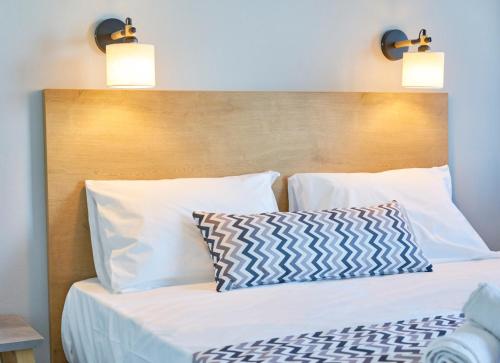 a bed with white pillows and a wooden headboard at Maistrali Sea View Apartments in Stalida