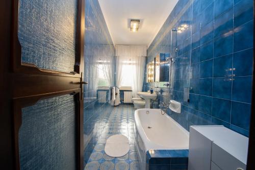 uma casa de banho com azulejos azuis, uma banheira e um WC. em Elegante appartamento di 200 mq con vista a Sanremo em Sanremo
