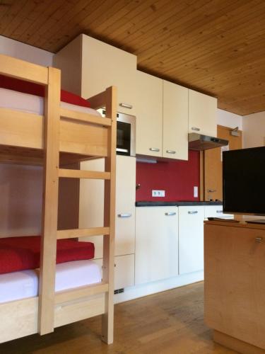 a room with a bunk bed and a kitchen at Wäldermetzge Hüttenzimmer und Wohnungen in Warth am Arlberg