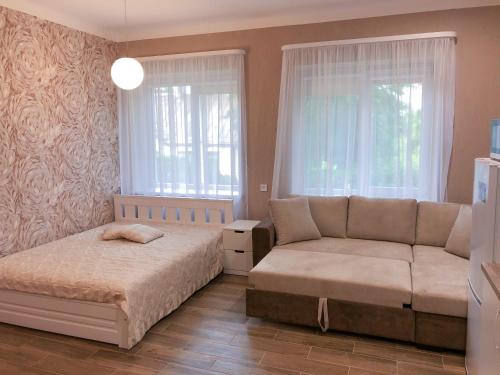 a bedroom with a bed and a couch and windows at Marsas in Zarasai