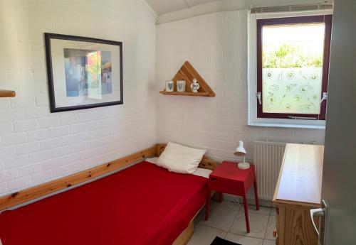Habitación pequeña con cama roja y ventana en Bungalow36 - Petten, en Petten