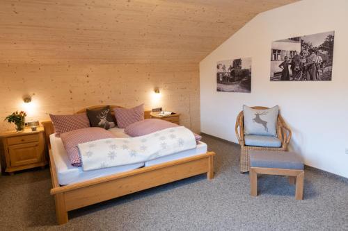 ein Schlafzimmer mit einem Bett und einem Stuhl in der Unterkunft Pension Hartmann in Fischen im Allgäu