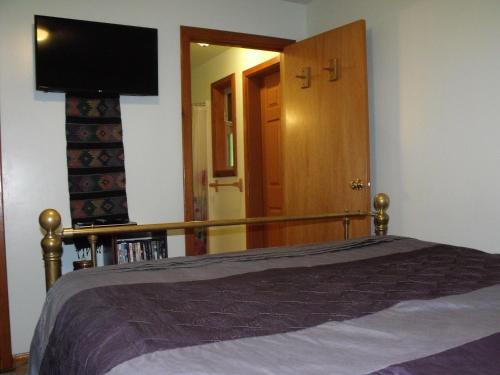 a bedroom with a bed and a flat screen tv at Summerhill Guest House in Tofino