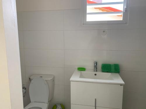 a white bathroom with a sink and a toilet at Ô TI JACKO in Le Gosier