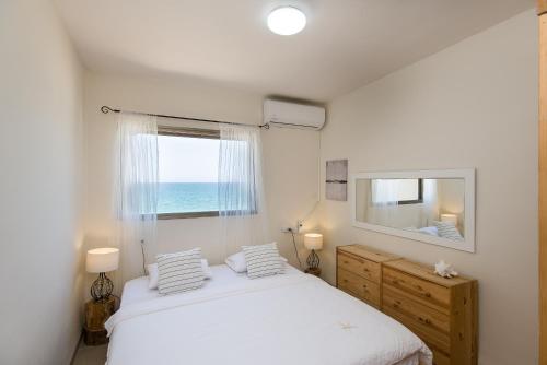 Un dormitorio blanco con una cama y una ventana. en Luminous Sea, en Haifa