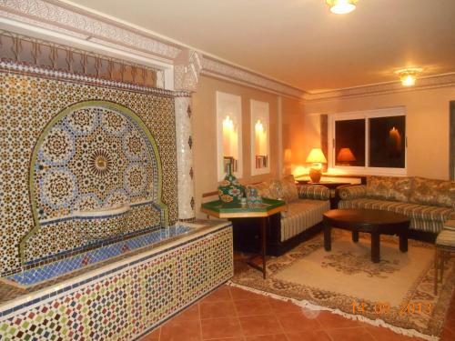 un soggiorno con divano e parete piastrellata di Tigmi Dar Samy a Bine el Ouidane
