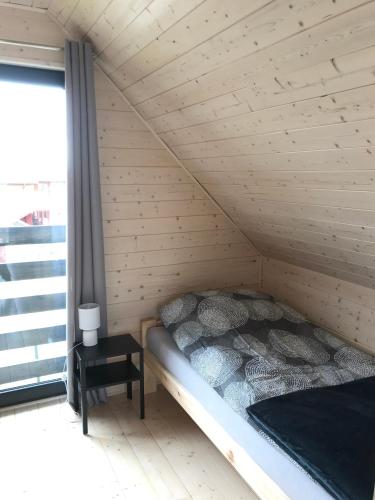 a bed in a wooden room with a window at White Houses Rewal in Rewal