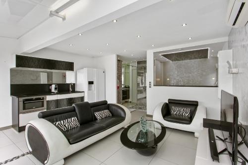 un salon avec un canapé noir et une table dans l'établissement Village Naturiste - La Villa Tentation Port Nature Luxe, au Cap d'Agde