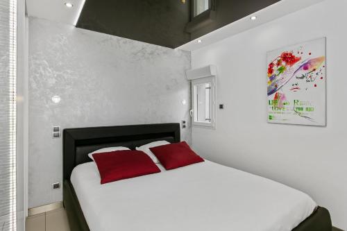 een slaapkamer met een wit bed en 2 rode kussens bij Village Naturiste - La Villa Tentation Port Nature Luxe in Cap d'Agde