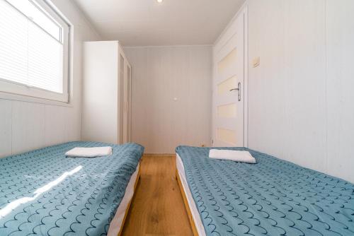 two twin beds in a room with a window at Domki u Polki in Sławoszyno