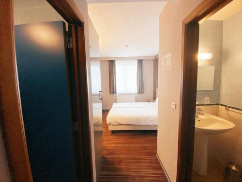 a room with a bed and a bathroom with a sink at Hotel les100ciels in Saint-Hubert