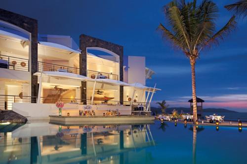 a villa with a swimming pool and a palm tree at Dreams Vallarta Bay Resorts & Spa - All Inclusive in Puerto Vallarta