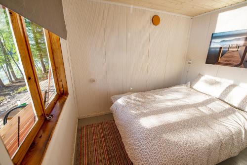 a small bedroom with a bed and a window at Lingonberry Pieni mökki saunalla in Mikkeli