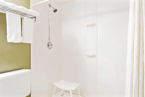 uma casa de banho com um chuveiro, um WC branco e um banco em Super 8 by Wyndham Eureka/Six Flags Nearby em Eureka