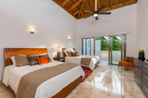 een slaapkamer met 2 bedden en een plafondventilator bij Unique Private Villa with Pools and Golf Cart in La Romana