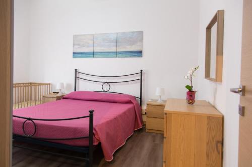 マリーナ・ディ・ラグーザにあるAppartamento Nettunoのベッドルーム1室(ピンクの毛布付きのベッド1台付)
