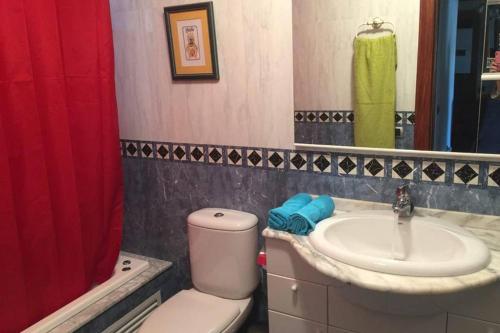 a bathroom with a toilet and a sink and a red shower curtain at APARTAMENTO 1ºLINEA PLAYA PONIENTE in Gijón