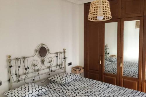 a bedroom with a bed with two pillows and a mirror at APARTAMENTO 1ºLINEA PLAYA PONIENTE in Gijón