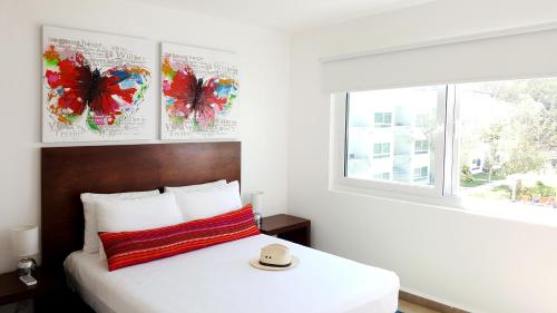 サンタ・クルス・ウアトゥルコにある9 Bahias Condos con club de playaの帽子が置かれたベッドのある寝室