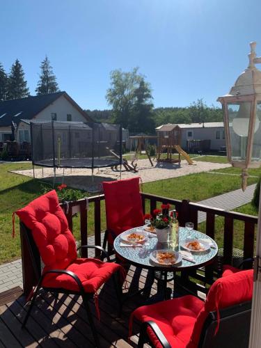 a table and chairs on a deck with a table and chairs at MIĘDZY NAMI domki nad jeziorem in Kołczewo