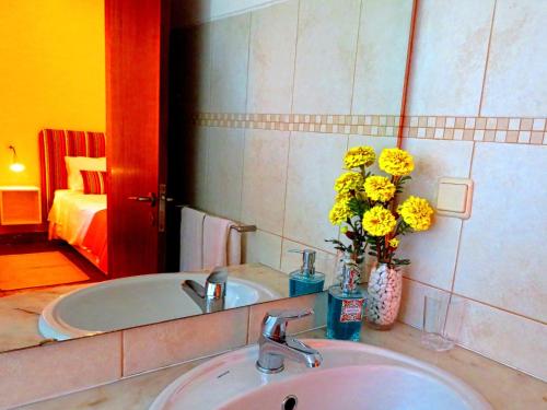 a bathroom with a sink and a tub with yellow flowers at Villa Esmeralda in Albufeira