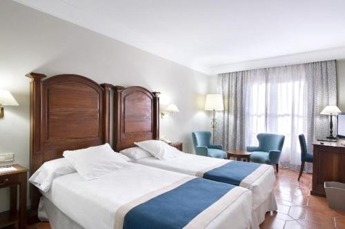 a hotel room with two beds and two chairs at Parador de Alcañiz in Alcañiz
