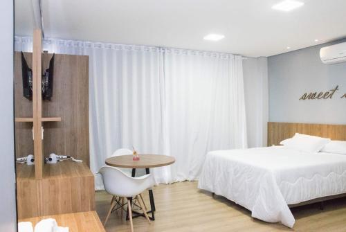 a bedroom with a bed and a table with a chair at Hotel Alvorada - Trindade do Sul in Trindade