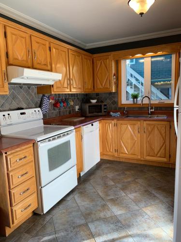 una cocina con electrodomésticos blancos y armarios de madera en Le 154 Jacques-Cartier en Gaspé