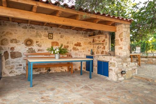 a patio with a blue table in front of a stone wall at Janakis Garden Livadi Beach in (( Spile ))