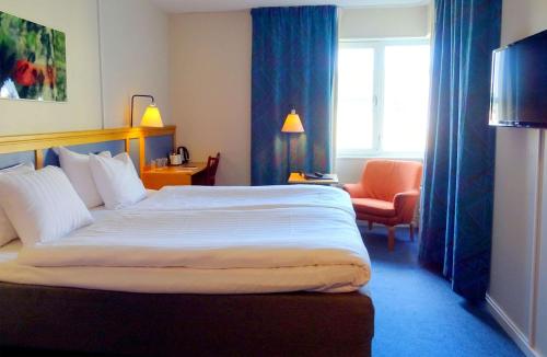 a hotel room with a large bed and a chair at Hotell Erikslund in Ängelholm