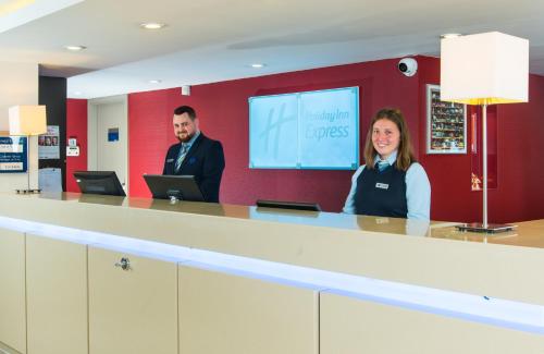 a man and a woman standing in front of a tv at Holiday Inn Express Milton Keynes, an IHG Hotel in Milton Keynes