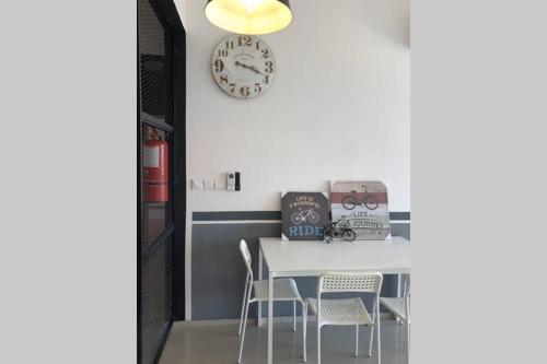 a dining room with a table and chairs and a clock at Enjoy Modern, Spacious, Peaceful stay with Lake view - Gravit8 in Klang