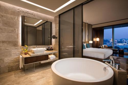 ein Badezimmer mit einer Badewanne und ein Schlafzimmer mit einem Bett in der Unterkunft HUALUXE Xiamen Haicang Habour View - An IHG Hotel in Xiamen