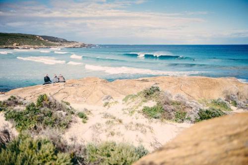 two people sitting on top of a beach with the ocean at Arthouse Six in Margaret River Town