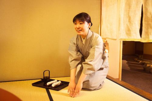 a woman sitting on a bed in a room at Honjin Hiranoya Kachoan in Takayama