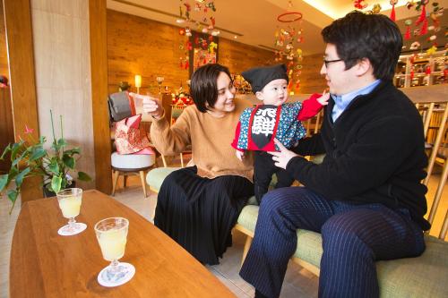 a man and woman holding a baby in a restaurant at Honjin Hiranoya Kachoan in Takayama