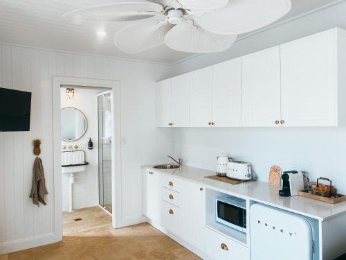 a kitchen with white cabinets and a ceiling fan at Pineapple Studio Byron Bay in Byron Bay
