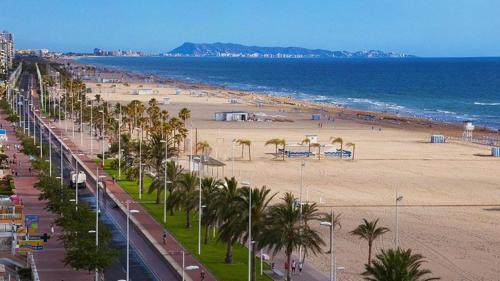 widok na plażę z palmami i oceanem w obiekcie Infante II Primera Linea Playa De Gandia SOLO FAMILIAS w mieście Playa de Gandia