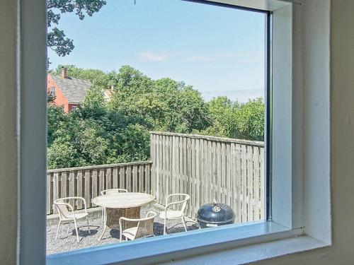 グドイェムにある2 person holiday home in Gudhjemのパティオ(テーブル、椅子付)の窓から景色を望めます。